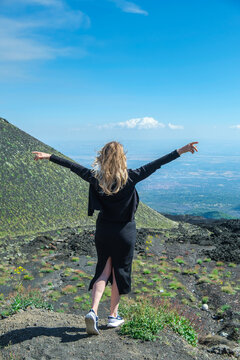 Rear view of a carefree woman standing with her arms outstretched on Mt Etna, Catania, Sicily, Italy