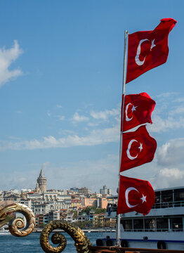 Turkish flags blowing in the wind on the waterfront with the Galata Tower in the distance, Istanbul, Turkey