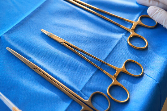 Clinical team prepares the necessary metal surgical tools on a blue table to ensure a safe and sterile operating environment
