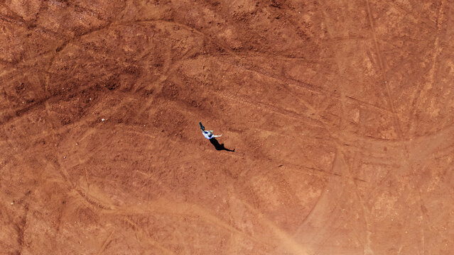Aerial view of a woman holding a camera standing in the Red Desert Nira Lefkada, Lefkada island, Greece