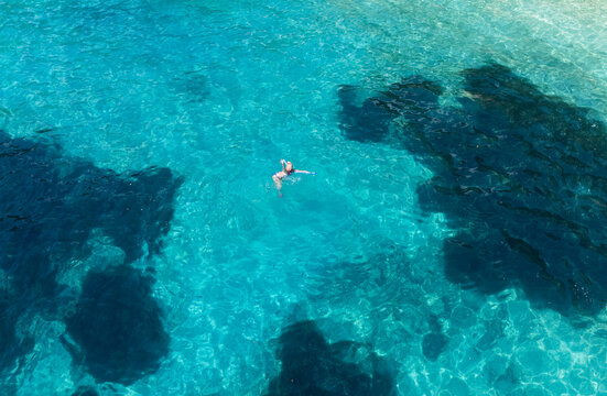 Aerial view of a Woman swimming in crystal clear turquoise waters of the Ionian sea, Lefkada island, Greece