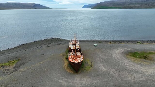 Aerial view of the rusted steel hull of the Gardar BA 64 shipwreck resting on a remote beach in Saudlauksdalur, Vesturbyggd, Iceland.