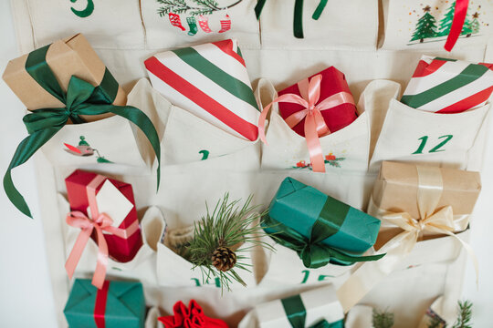 Close-up of part of a Traditional Christmas advent calendar with assorted wrapped gifts hanging on a white wall