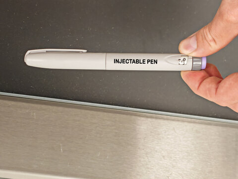 INJECTABLE PEN pharmaceutical dosage form and drug delivery concept held by quality control inspector on pharmaceutical production line