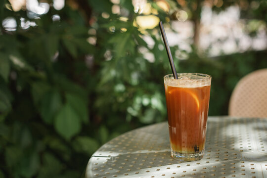 Close-up of an iced espresso tonic with ice cubes on an outdoor cafe table on a summer day