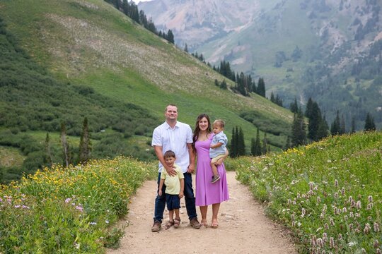 Family portrait of a couple with their two young sons standing on a footpath in Albion Basin Meadow, Albion Basin, Little Cottonwood Canyon, Utah, USA
