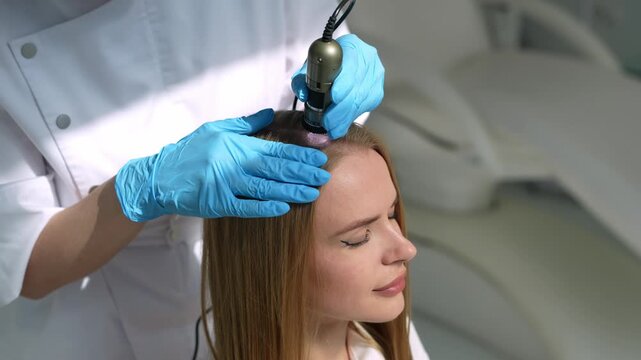 Trichologist examining patient scalp with a digital dermatoscope in a clinic 4k video. Scalp examination by a dermatologist using a handheld trichoscope device