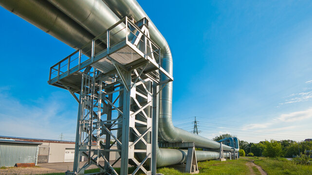 The photo shows a pipeline against a blue sky with green grass in the foreground