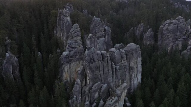 Aerial view of towering sandstone rock formations rising above a dense pine forest in the Adrspach-Teplice Rocks in Adrspach, Hradec Kralove Region, Czechia.