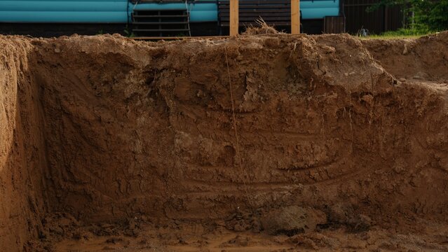 Freshly excavated soil forming the side of a deep trench on a construction site, preparing the ground for a new building project foundation