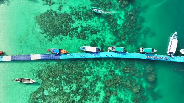 Aerial view of boats moored at a floating pier over turquoise waters at Ko Racha Yai in Rawai, Phuket, Thailand.