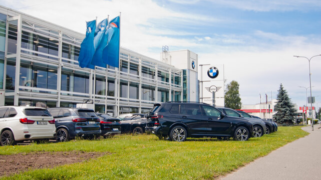 Riga, Latvia - July 15, 2026: The photo shows new BMW cars with a car dealership building and a billboard with the BMW logo in the background