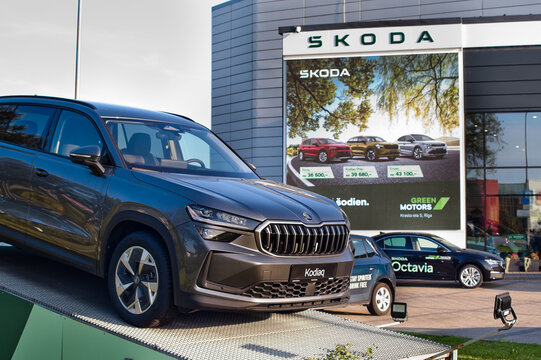 Riga, Latvia - July 30, 2026: A new Skoda Kodiaq car on the street near a car dealership with an advertising billboard in the background