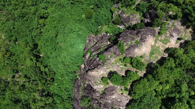Majestic granite stone cliff and lush green forest in Nakhon Nayok province, Thailand.