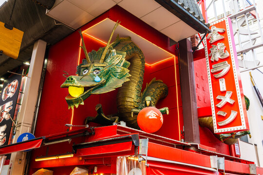 Storefront of Kinryu Ramen in Dotonbori with its landmark giant green dragon breaking through the wall, one of Osaka's most famous symbols and the area's cultural landmark since 1982.