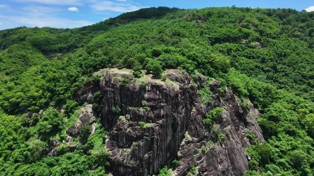 Majestic granite stone cliff and lush green forest in Nakhon Nayok province, Thailand.
