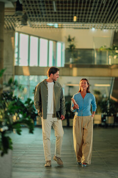 Diverse business colleagues walking and talking together in modern office lobby, discussing work with positive attitude