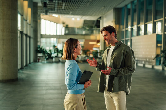 Business colleagues having casual conversation in modern office lobby, discussing work during an informal meeting