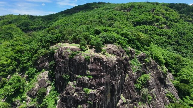 Majestic granite stone cliff and lush green forest in Nakhon Nayok province, Thailand.