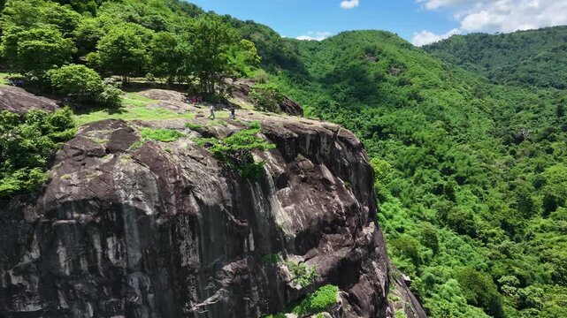 Majestic granite stone cliff and lush green forest in Nakhon Nayok province, Thailand.