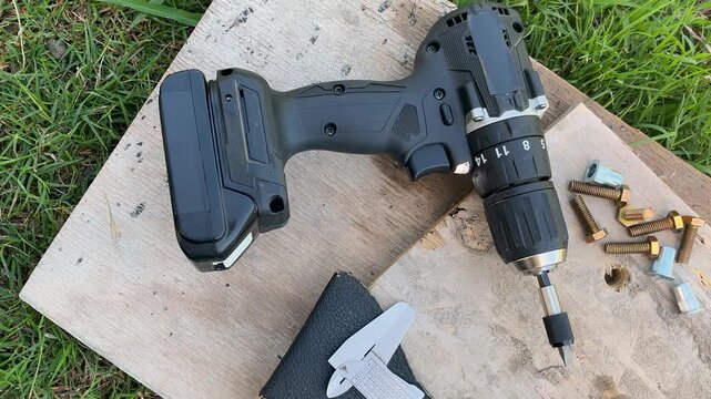 Top view of a professional cordless screwdriver next to tools and items for home improvement and workshop tasks.