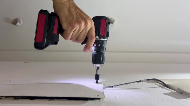 Close-up of construction worker's hand using a cordless screwdriver during a home renovation
