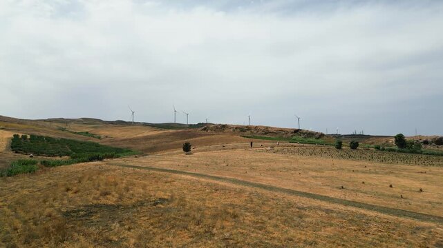 Aerial view of wind turbines and rolling hills in the rural landscape of Trapani, Sicily, Italy.