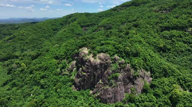 Majestic granite stone cliff and lush green forest in Nakhon Nayok province, Thailand.