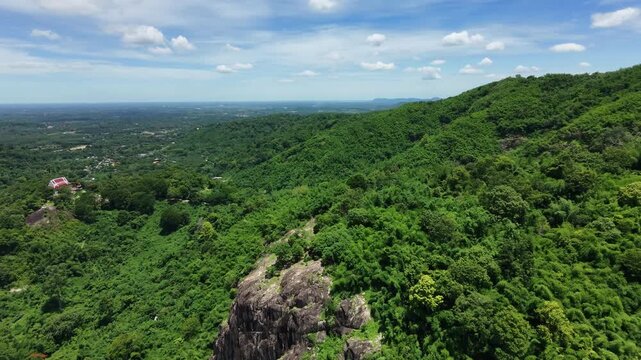Majestic granite stone cliff and lush green forest in Nakhon Nayok province, Thailand.