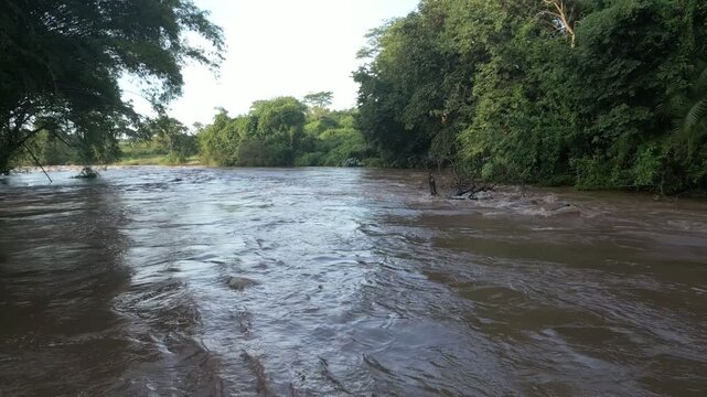 Aerial view of a muddy river flowing through dense green forest vegetation in Kenya. River Sagana Tana River, Sagana, Kirinyaga County, Kenya.