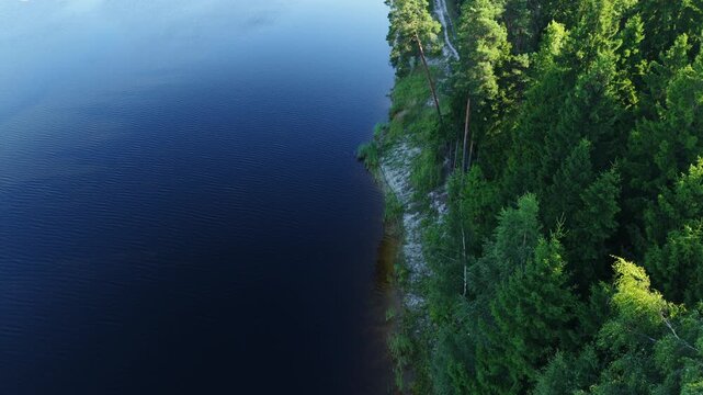 Aerial view of Kalnciems Dolomite Quarry with deep blue water and dense pine forest along the rocky bank in Valgunde Parish, Jelgava Municipality, Latvia.