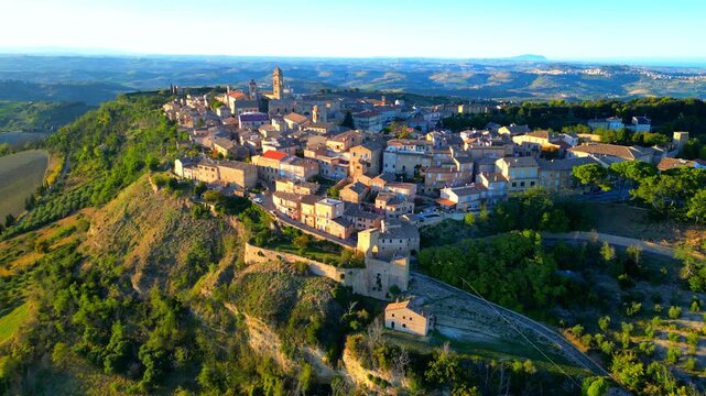 Complete aerial truck left pan right overview of the Monterubbiano town centre, a shot encompassing the manifold buildings on this high promontory, including belltowers, clocktowers, houses, and trees