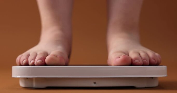 Overweight woman stepping on scale against brown background, closeup