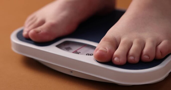 Overweight woman on scale against brown background, closeup. Camera moving left