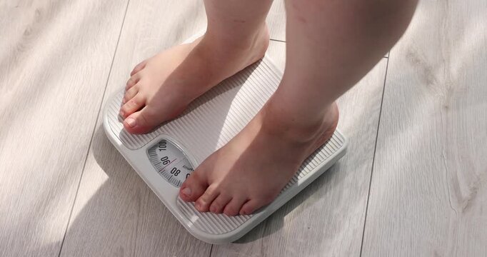 Overweight woman stepping on scale at home, closeup
