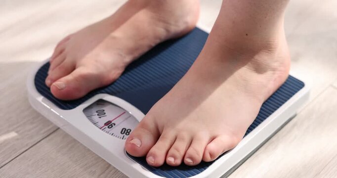 Overweight woman on scale at home, closeup