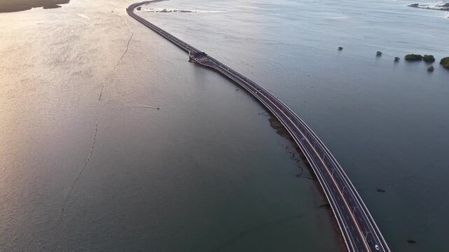 Aerial view of the Mandara Toll Road stretching across the water at sunset in Kabupaten Badung, Bali, Indonesia.