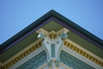 Victorian house roof corner with decorative wood trim against blue sky © Simone