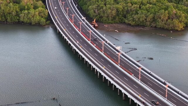 Aerial view of the Mandara Toll Road stretching over the water, surrounded by lush mangrove forests in Kabupaten Badung, Bali, Indonesia.