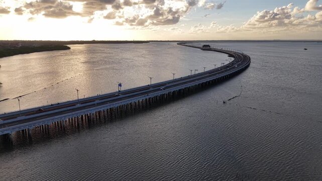 Aerial view of the Mandara Toll Road stretching across the water at sunset in Kabupaten Badung, Bali, Indonesia.