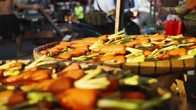 Close-Up of a Market Vendor Adding Fresh Carrots to a Vegetable Display