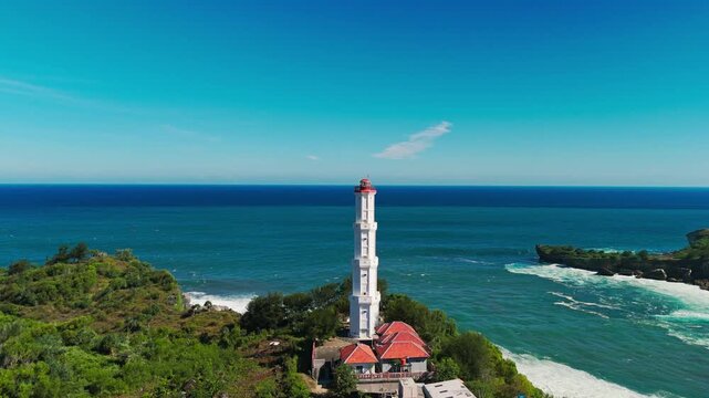 Aerial view of Baron Lighthouse standing on the cliff edge overlooking the Indian Ocean at Baron Beach in Tanjungsari, Special Region of Yogyakarta, Indonesia.
