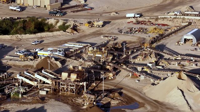 Aerial view of an aggregate operation and gravel pit in Bluffdale, featuring heavy machinery, conveyor belts, and piles of refined sand and construction gravel in Bluffdale, Utah, United States.
