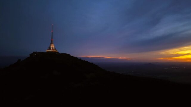 Aerial view of Jested Tower illuminated against the twilight sky atop the mountain peak in Liberec, Liberecky kraj, Czechia.