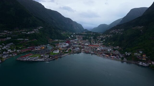 Aerial view of the town of Odda situated between steep mountains and the fjord, featuring harbor buildings and residential areas in Odda, Vestland, Norway.