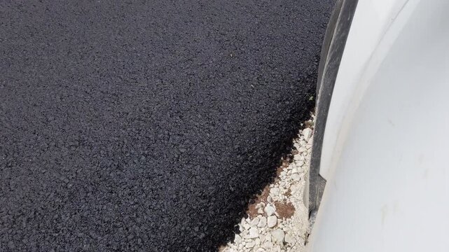 New asphalt paving process shown during road construction in a city area