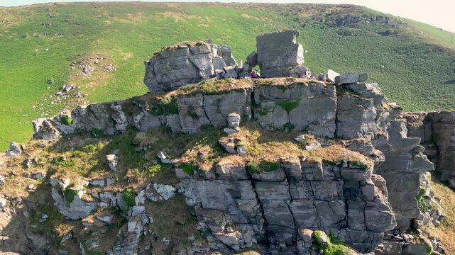 Aerial view of the rugged rock formations of the Valley of Rocks with green hills and a winding road in Lynton, England, United Kingdom.
