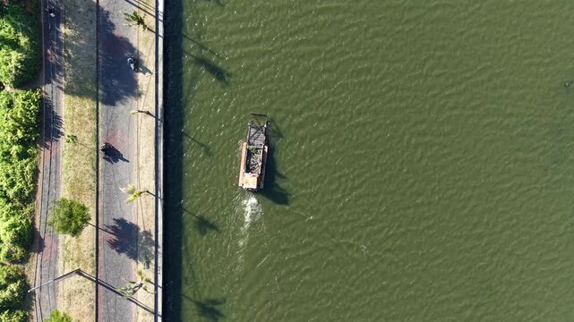 Aerial view of the floating solar power plant at Muara Nusa Dua reservoir with a boat on the water near a paved path in Kecamatan Denpasar Selatan, Bali, Indonesia.