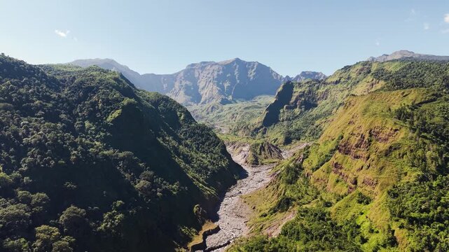 Aerial view of a deep mountain valley with steep green slopes and a rocky riverbed in Makassar, South Sulawesi, Indonesia.