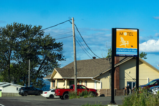 Gaspesie, Quebec, 11 July 2026 : Motel sign advertising "Carleton-sur-Mer" with kitchenette and sea view, in front of a building with parked cars.